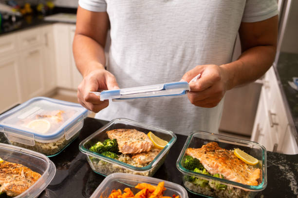 Filipino man putting away meal prep containers salmon