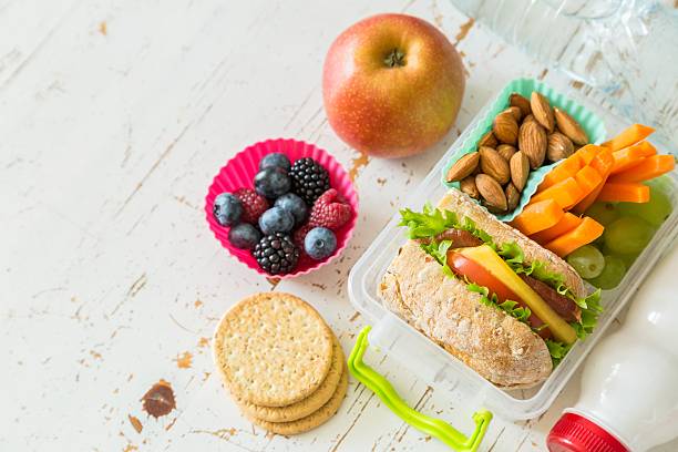 School lunch box with books and pencils in front of black board, copy space
